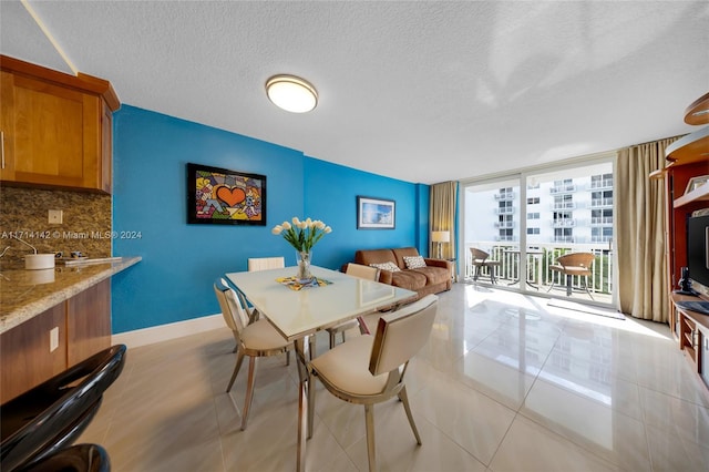 tiled dining space with a textured ceiling and expansive windows