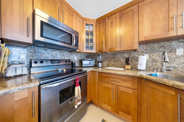 kitchen with light stone countertops, sink, appliances with stainless steel finishes, and tasteful backsplash