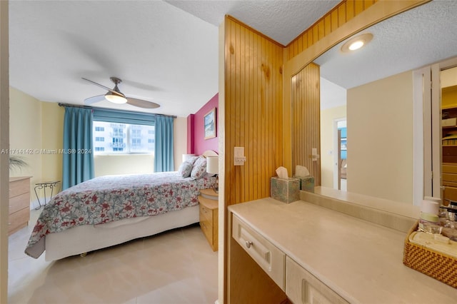 bedroom featuring wooden walls, ceiling fan, and a textured ceiling