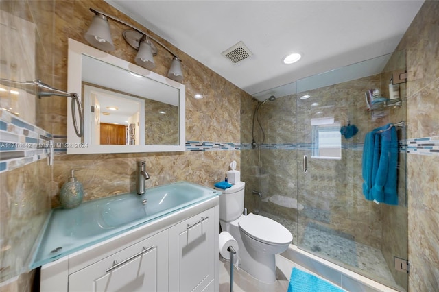 bathroom with vanity, a shower with door, toilet, tile walls, and tasteful backsplash