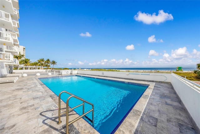 view of swimming pool with a water view and a patio area