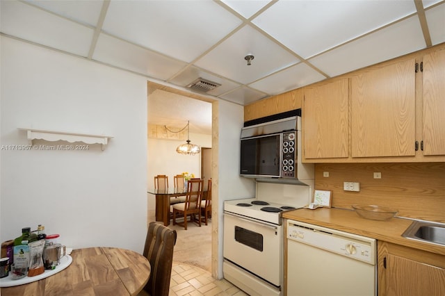 kitchen featuring light brown cabinets, white appliances, a drop ceiling, and a notable chandelier