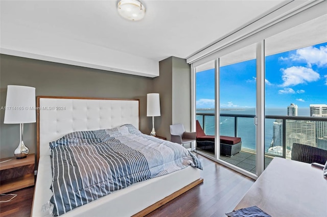 bedroom featuring multiple windows, a water view, expansive windows, and access to exterior