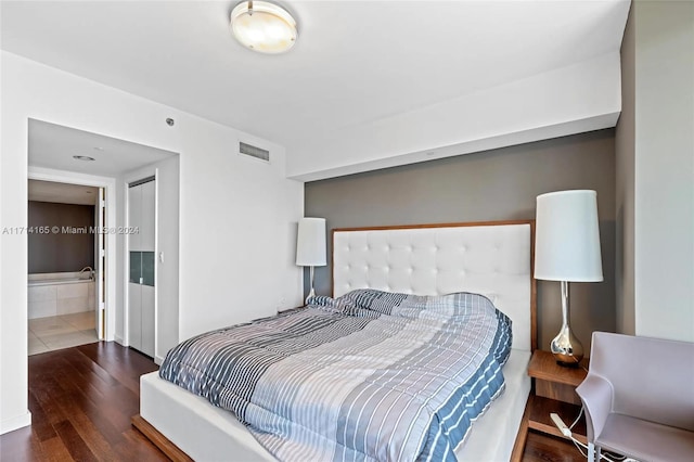 bedroom with dark hardwood / wood-style flooring and ensuite bath