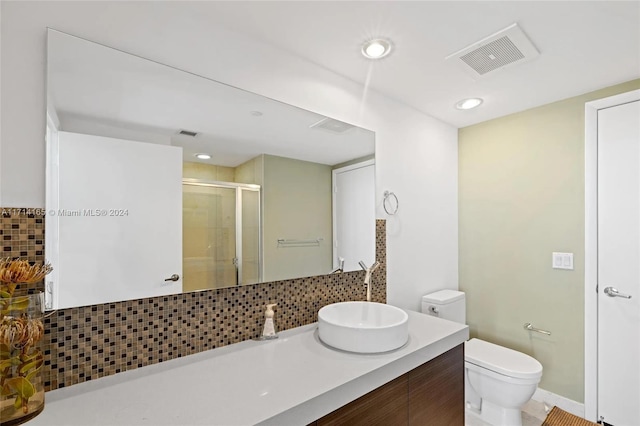 bathroom with backsplash, vanity, a shower with shower door, and toilet