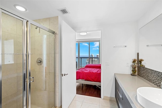 bathroom with tile patterned flooring, vanity, a water view, and a shower with shower door