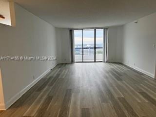 spare room with floor to ceiling windows and dark hardwood / wood-style floors