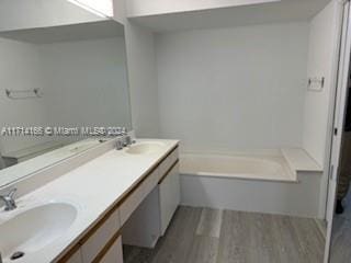 bathroom with a bathing tub, vanity, and wood-type flooring