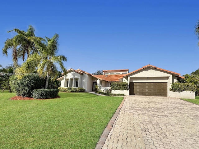 mediterranean / spanish-style house with a garage and a front lawn