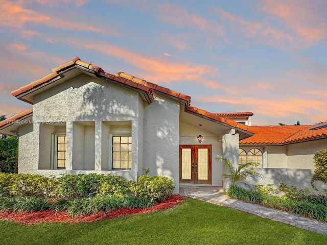 view of front of house with french doors and a yard