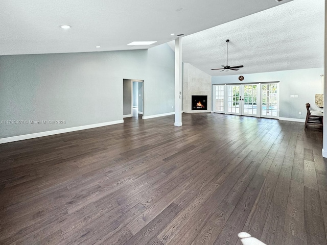 unfurnished living room featuring dark hardwood / wood-style floors, high vaulted ceiling, ceiling fan, a premium fireplace, and a textured ceiling