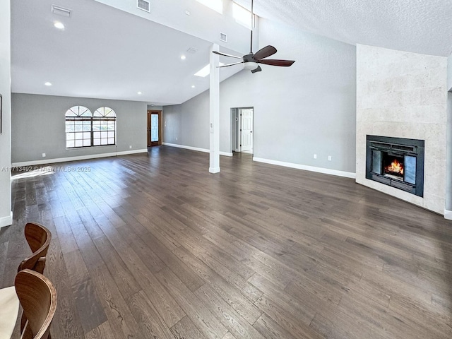 unfurnished living room with vaulted ceiling, a textured ceiling, dark hardwood / wood-style floors, ceiling fan, and a fireplace