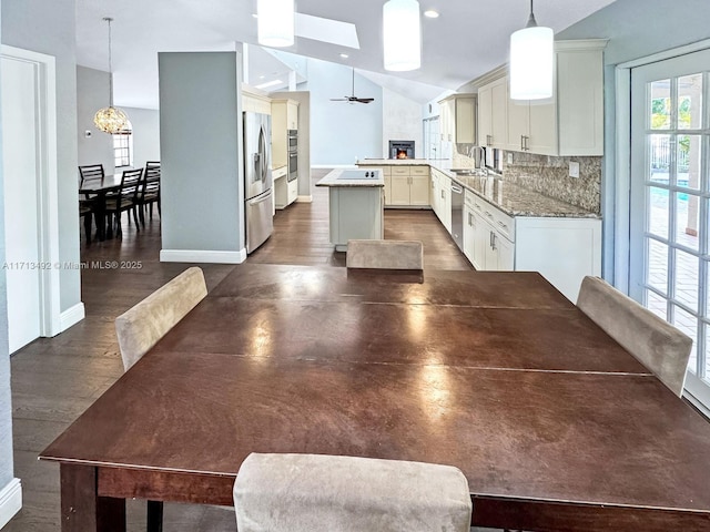 kitchen featuring sink, decorative light fixtures, appliances with stainless steel finishes, kitchen peninsula, and decorative backsplash