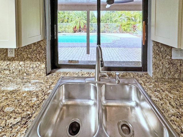 room details with tasteful backsplash, ceiling fan, sink, and white cabinets