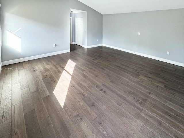 spare room with lofted ceiling and dark hardwood / wood-style flooring