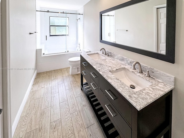 full bathroom featuring vanity, shower / bath combination with glass door, and toilet