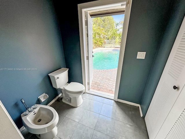 bathroom with a bidet, toilet, and tile patterned flooring