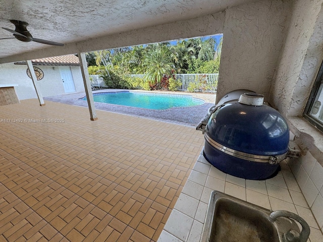 view of swimming pool with ceiling fan, area for grilling, and a patio area