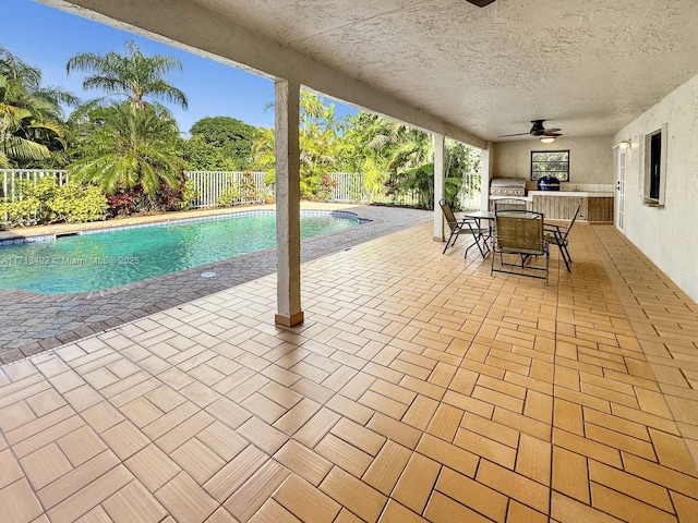 view of pool with an outdoor kitchen, a grill, ceiling fan, and a patio area