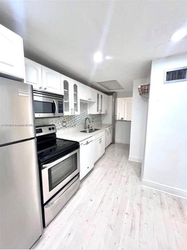 kitchen featuring white cabinets, appliances with stainless steel finishes, light wood-type flooring, and sink