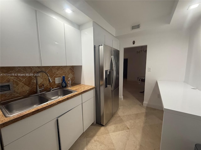 kitchen featuring white cabinets, sink, stainless steel fridge, and decorative backsplash