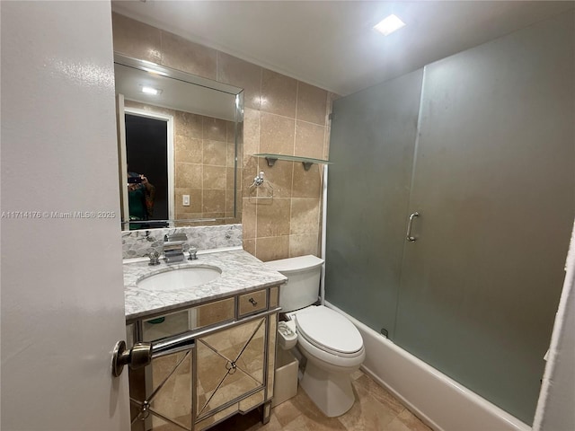 full bathroom featuring shower / bath combination with glass door, tile walls, vanity, tasteful backsplash, and toilet