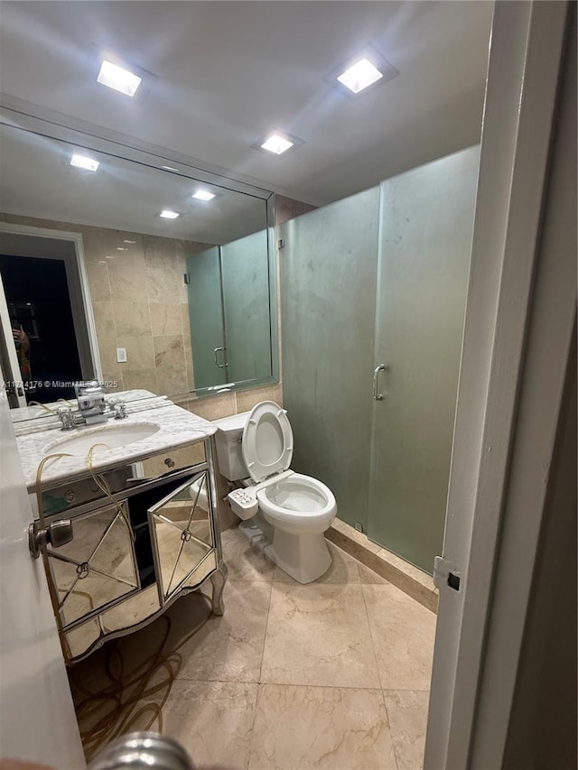 bathroom featuring vanity, tile walls, an enclosed shower, and toilet