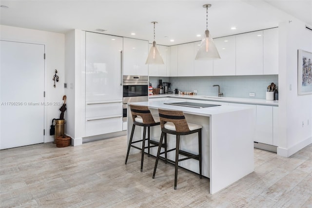 kitchen with white cabinets, black electric stovetop, decorative light fixtures, and tasteful backsplash