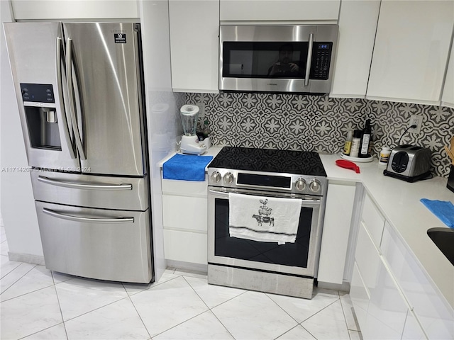 kitchen featuring white cabinets, appliances with stainless steel finishes, backsplash, and light tile patterned floors