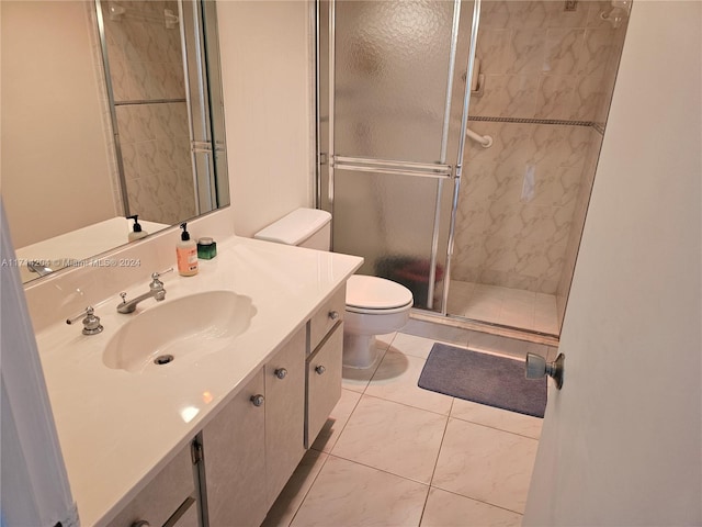 bathroom featuring tile patterned flooring, vanity, toilet, and walk in shower