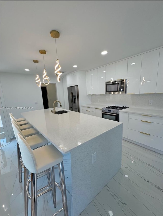 kitchen with white cabinets, an island with sink, appliances with stainless steel finishes, tasteful backsplash, and decorative light fixtures