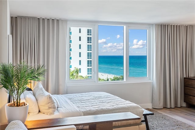 bedroom with hardwood / wood-style floors and a water view