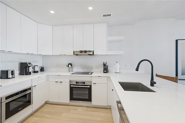 kitchen with white cabinets, stainless steel oven, and sink