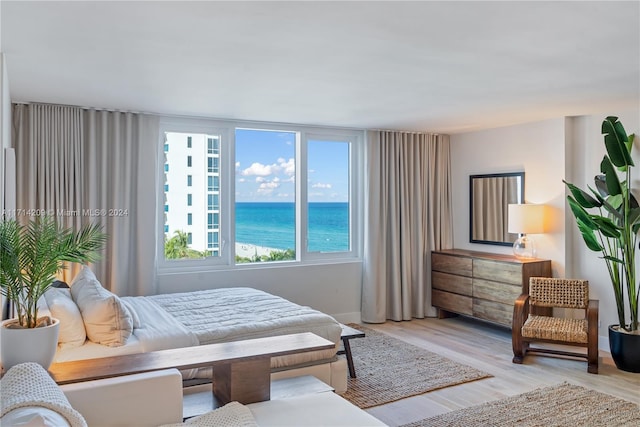 bedroom with a water view and light hardwood / wood-style flooring