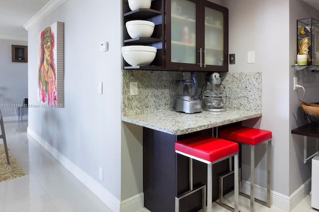 kitchen with light stone countertops, glass insert cabinets, backsplash, and ornamental molding