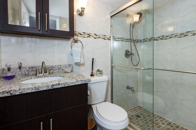 full bath featuring tile walls, toilet, vanity, a shower stall, and backsplash