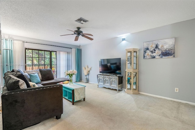 living room with light carpet, ceiling fan, and a textured ceiling