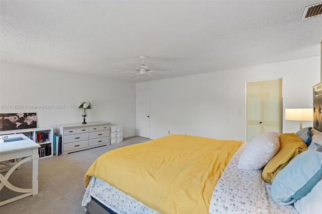 carpeted bedroom with a textured ceiling, a closet, and ceiling fan