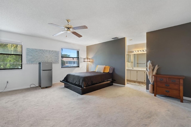 bedroom with ceiling fan, stainless steel fridge, multiple windows, and ensuite bath