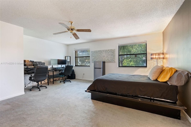 carpeted bedroom featuring a textured ceiling, stainless steel refrigerator, and ceiling fan