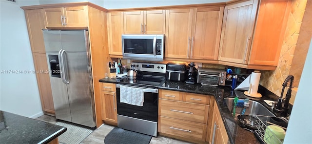 kitchen featuring tasteful backsplash, dark stone countertops, sink, and stainless steel appliances