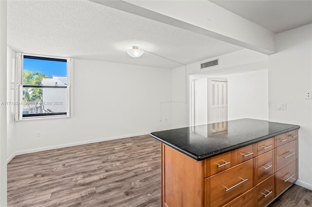 kitchen with dark hardwood / wood-style flooring, dark stone countertops, and a textured ceiling