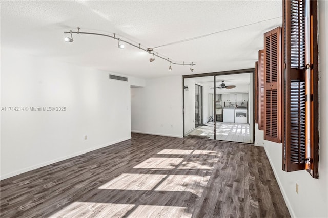 unfurnished room with a textured ceiling, separate washer and dryer, ceiling fan, and dark hardwood / wood-style floors