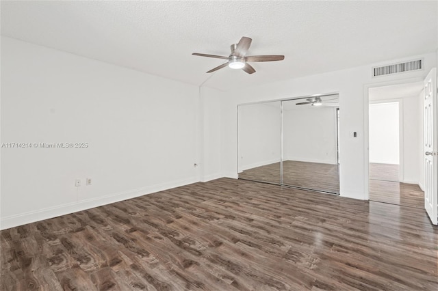 unfurnished bedroom featuring dark hardwood / wood-style flooring, ceiling fan, a closet, and a textured ceiling