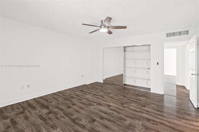 unfurnished bedroom featuring a textured ceiling, ceiling fan, a closet, and dark hardwood / wood-style floors