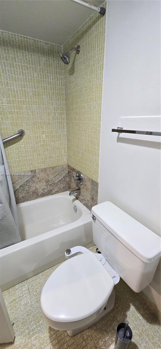 bathroom featuring tiled shower / bath combo and toilet