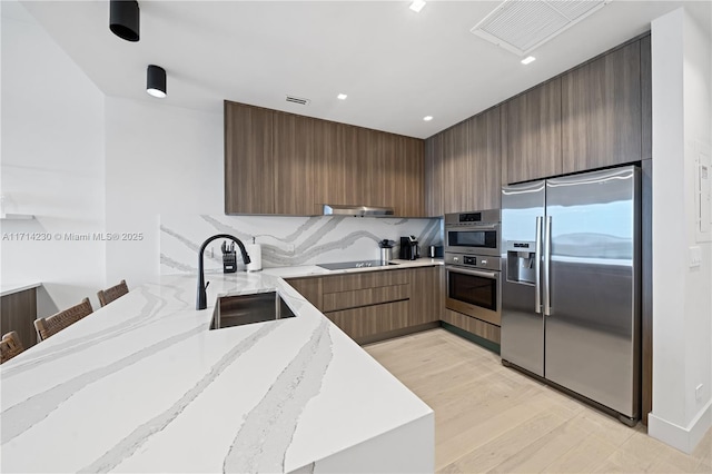 kitchen featuring a breakfast bar, exhaust hood, sink, light hardwood / wood-style flooring, and stainless steel fridge with ice dispenser