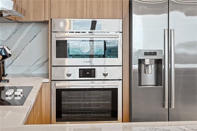 kitchen with light stone countertops, appliances with stainless steel finishes, and decorative backsplash