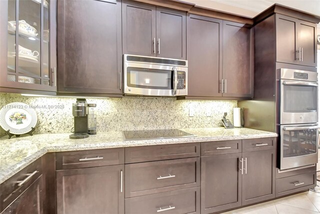 kitchen with light stone counters, dark brown cabinetry, appliances with stainless steel finishes, and tasteful backsplash