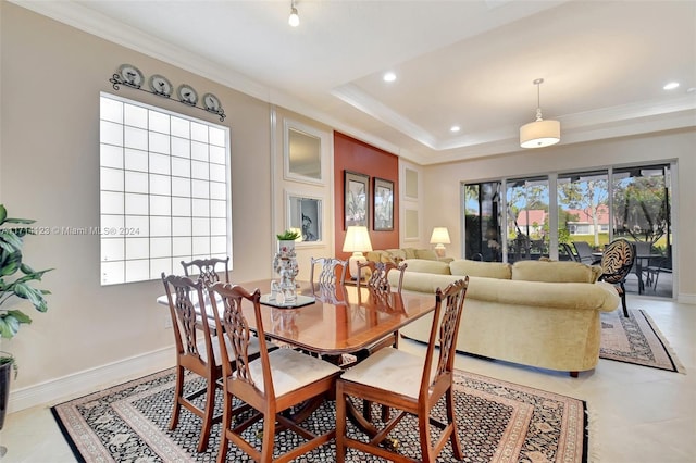 dining room with light tile patterned floors, a raised ceiling, and ornamental molding